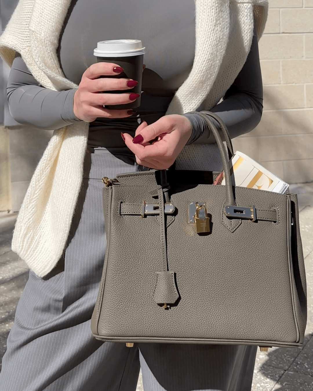 Sac à main en cuir beige porté avec cadenas doré